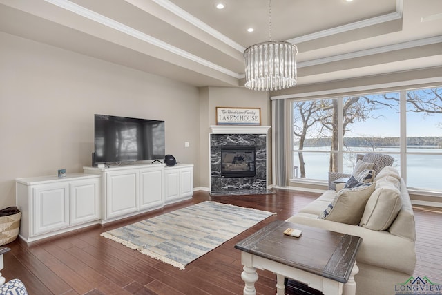 living room featuring an inviting chandelier, a tray ceiling, a wealth of natural light, and dark hardwood / wood-style floors