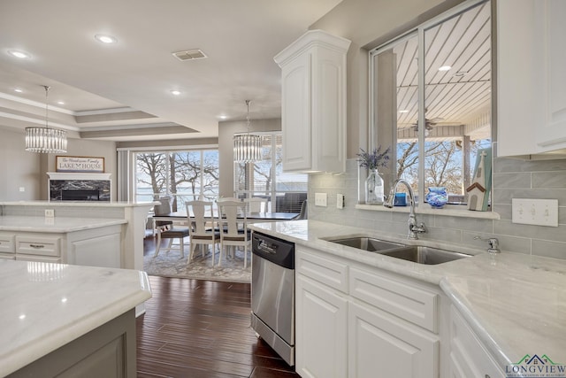 kitchen with sink, white cabinetry, a notable chandelier, a tray ceiling, and stainless steel dishwasher