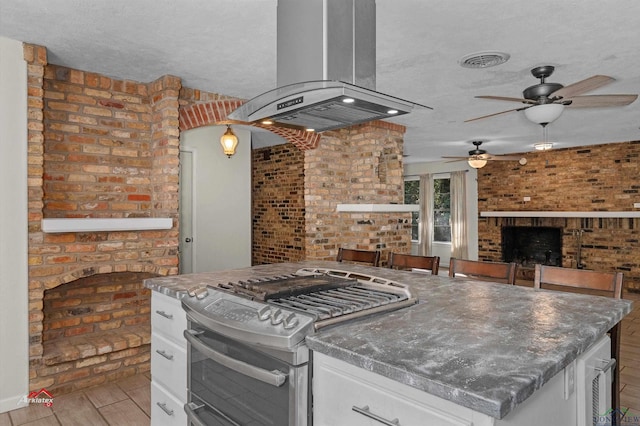 kitchen featuring island range hood, white cabinetry, a textured ceiling, and gas stove