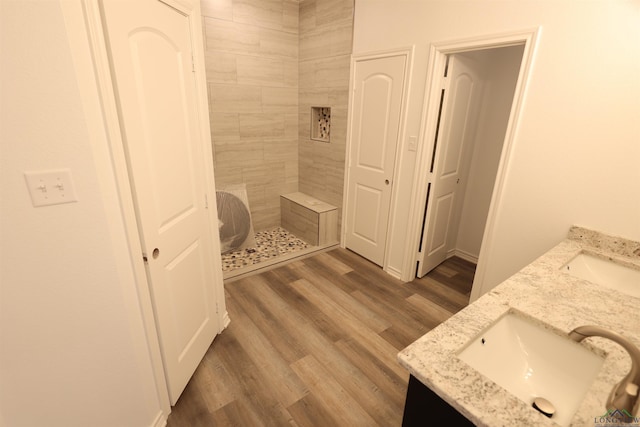 bathroom with a tile shower, vanity, and hardwood / wood-style flooring