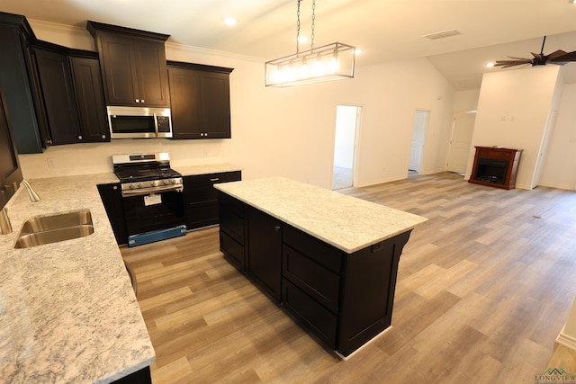 kitchen featuring ceiling fan, sink, gas range oven, decorative light fixtures, and a kitchen island