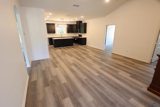 kitchen with appliances with stainless steel finishes, sink, pendant lighting, hardwood / wood-style flooring, and a kitchen island