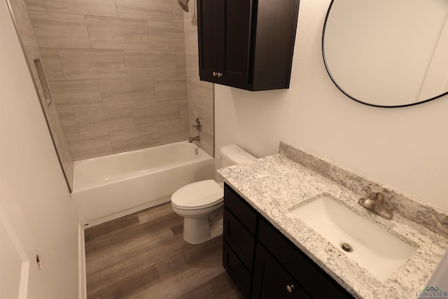 full bathroom featuring vanity, hardwood / wood-style floors, tiled shower / bath combo, and toilet