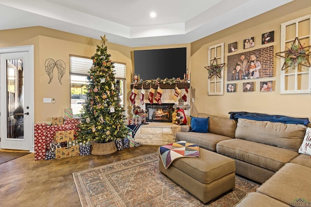 living room with a stone fireplace and a tray ceiling