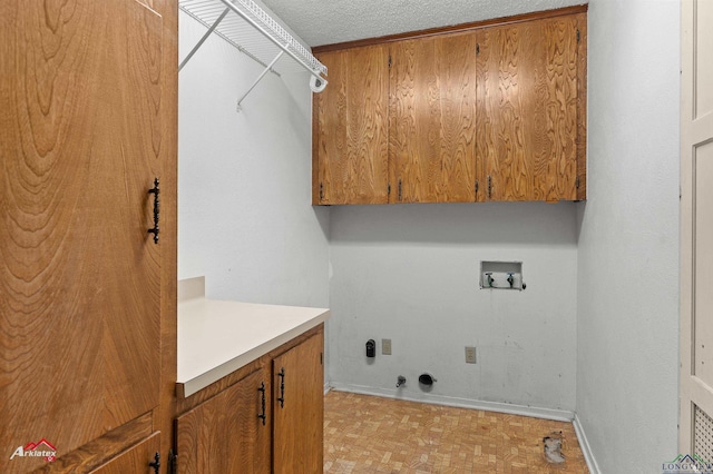 laundry area featuring a textured ceiling, gas dryer hookup, washer hookup, baseboards, and cabinet space