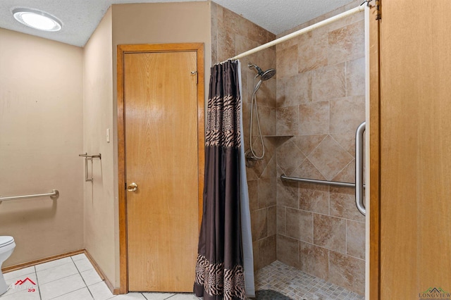 bathroom with tile patterned floors, toilet, a shower stall, a textured ceiling, and baseboards
