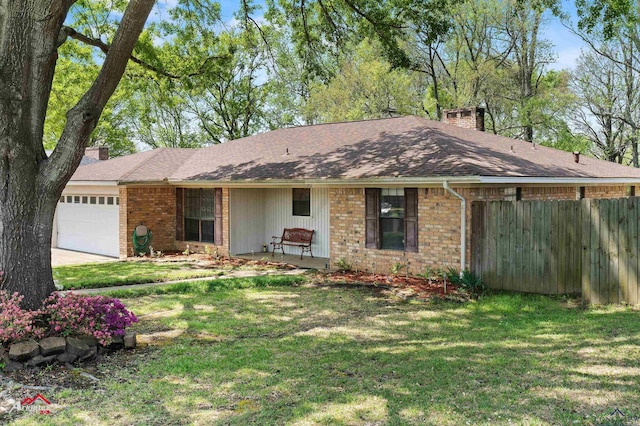 ranch-style house with fence, an attached garage, a chimney, a front yard, and brick siding
