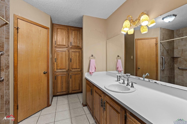 full bath with tile patterned floors, a tile shower, vanity, and a textured ceiling