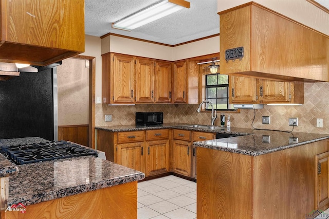 kitchen featuring black microwave, brown cabinetry, and a sink