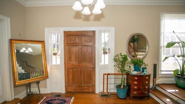 foyer entrance with a notable chandelier, crown molding, and hardwood / wood-style floors