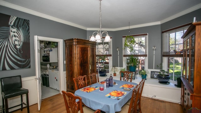 dining space featuring hardwood / wood-style floors, an inviting chandelier, and crown molding