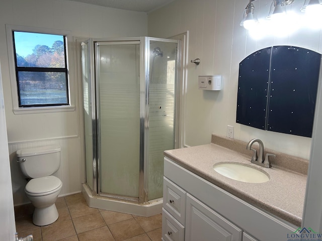 bathroom with toilet, vanity, tile patterned flooring, and a shower with shower door