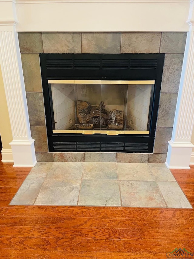 1928 Eastwood Dr, Henderson, TX 75652 - detailed view of a tile fireplace, decorative columns, baseboards, and wood finished floors