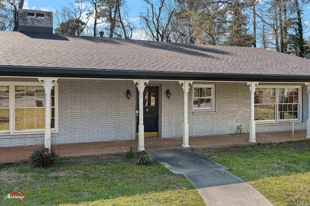 exterior space featuring a porch, brick siding, roof with shingles, a front lawn, and a chimney