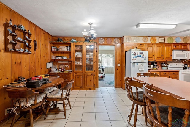 dining room with wood walls, light tile patterned flooring, a textured ceiling, and a chandelier