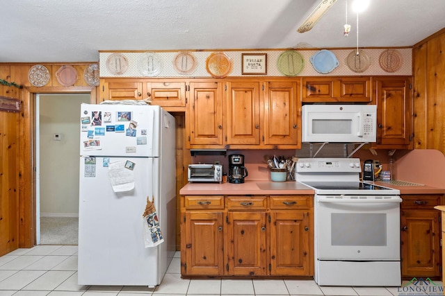 kitchen with a textured ceiling, light tile patterned floors, and white appliances