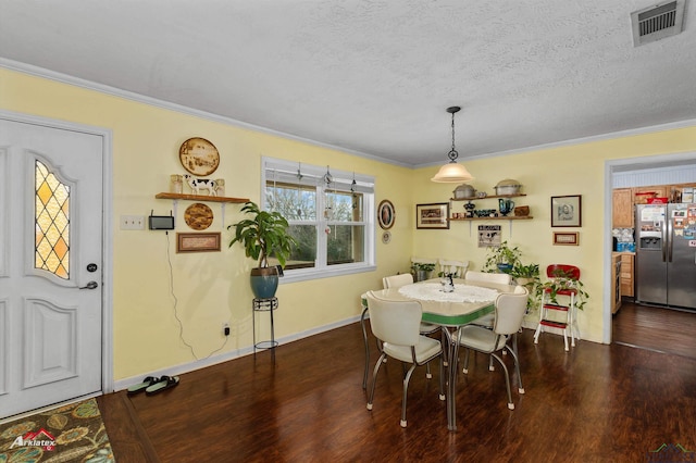 dining room featuring crown molding, dark wood-type flooring, and a textured ceiling