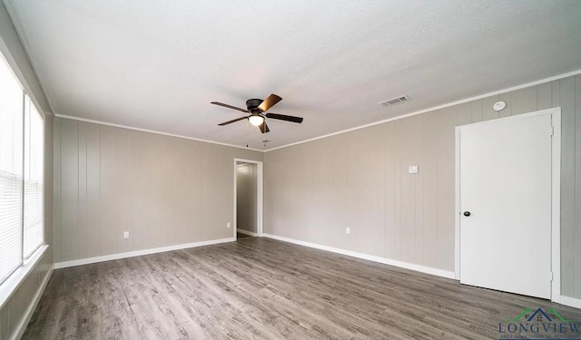 empty room with hardwood / wood-style flooring, plenty of natural light, and ornamental molding