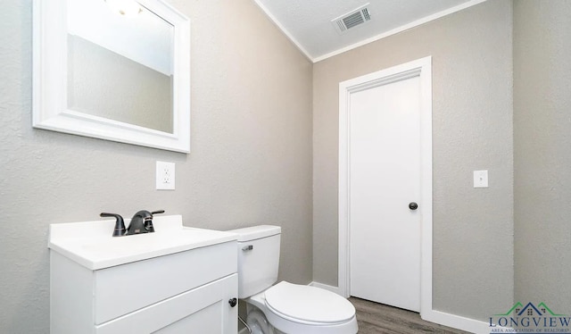 bathroom with vanity, toilet, wood-type flooring, and crown molding