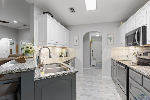 908 Victoria Dr, Longview, TX 75604 - kitchen featuring visible vents, a sink, arched walkways, and stainless steel appliances