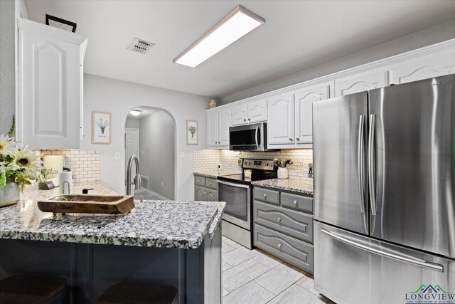 908 Victoria Dr, Longview, TX 75604 - kitchen featuring appliances with stainless steel finishes, backsplash, arched walkways, and visible vents