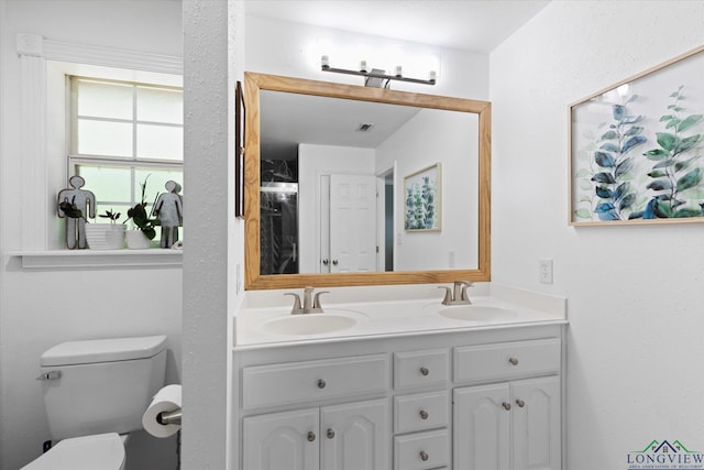 908 Victoria Dr, Longview, TX 75604 - bathroom featuring visible vents, a sink, double vanity, and toilet