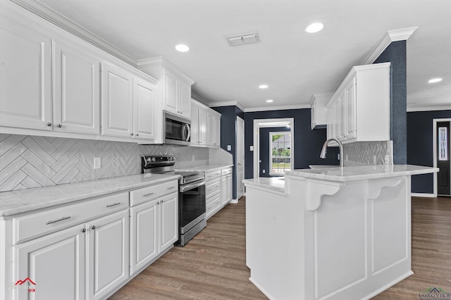 kitchen with white cabinets, recessed lighting, stainless steel appliances, ornamental molding, and a peninsula