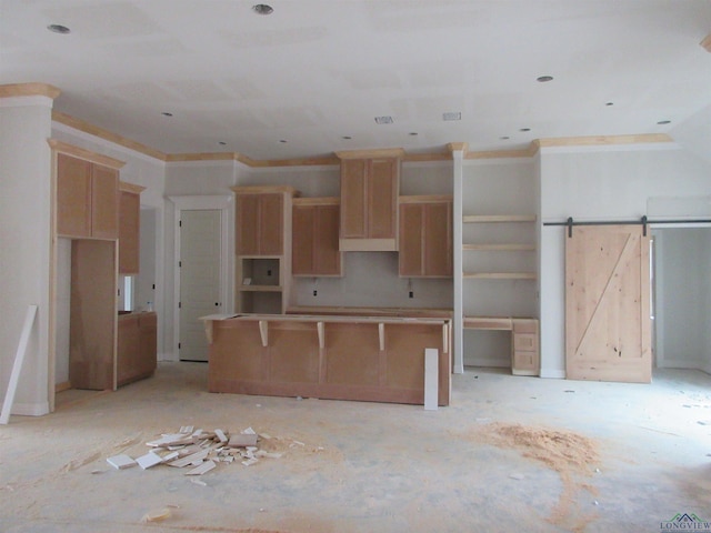 kitchen with a barn door, a kitchen island, and ornamental molding