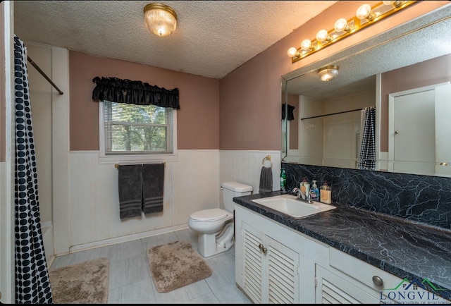 full bathroom with shower / bath combo with shower curtain, vanity, a textured ceiling, and toilet