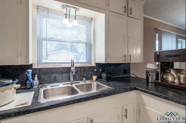 kitchen with white cabinets, sink, hanging light fixtures, decorative backsplash, and a textured ceiling