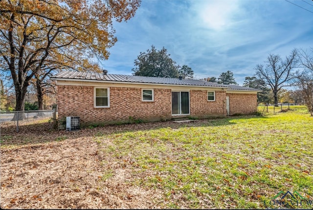 rear view of property featuring a lawn and cooling unit