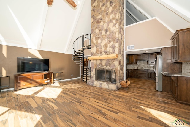 living room with a stone fireplace, beamed ceiling, high vaulted ceiling, and hardwood / wood-style floors