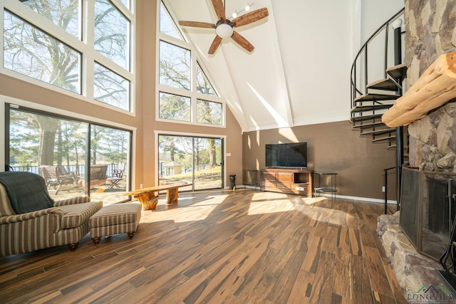 living room with a fireplace, a towering ceiling, hardwood / wood-style flooring, and ceiling fan