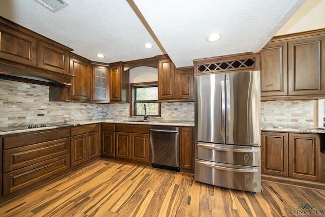 kitchen featuring light stone countertops, sink, appliances with stainless steel finishes, and dark wood-type flooring