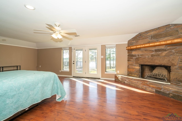 bedroom featuring ceiling fan, a stone fireplace, wood-type flooring, and lofted ceiling