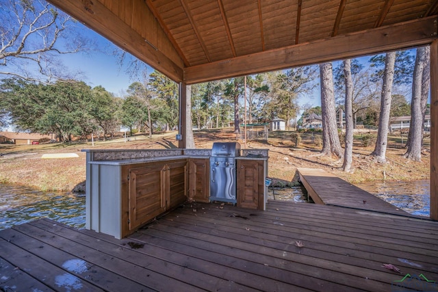 wooden deck with a water view and exterior kitchen