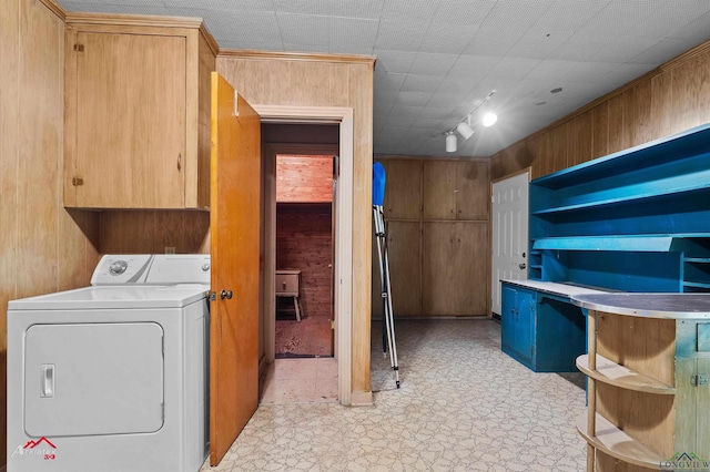 laundry area featuring light floors, cabinet space, washer / dryer, and wooden walls