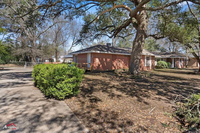 view of property exterior featuring brick siding and fence