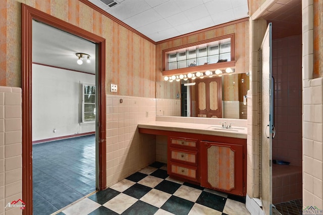 bathroom with ornamental molding, wainscoting, tile walls, and wallpapered walls