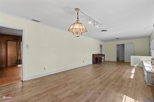 unfurnished living room featuring light wood-type flooring, visible vents, and ornamental molding