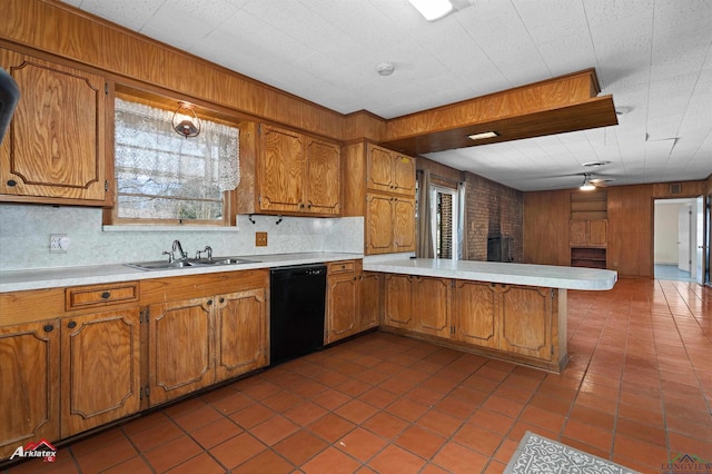 kitchen with a peninsula, brown cabinetry, black dishwasher, and light countertops