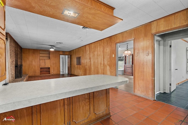 kitchen featuring brown cabinetry, light countertops, a fireplace, and wooden walls