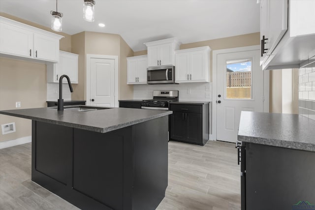 kitchen featuring stainless steel appliances, sink, tasteful backsplash, and a kitchen island with sink