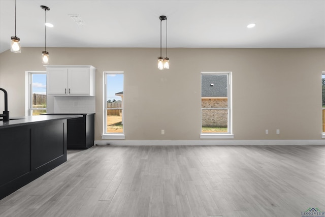 unfurnished living room featuring plenty of natural light, light hardwood / wood-style flooring, and sink