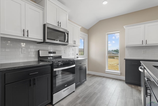 kitchen featuring tasteful backsplash, vaulted ceiling, light hardwood / wood-style floors, appliances with stainless steel finishes, and white cabinets