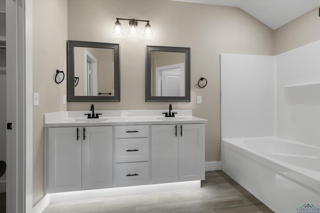 bathroom featuring hardwood / wood-style flooring, vanity, and vaulted ceiling