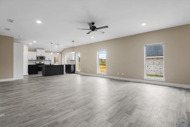 unfurnished living room with ceiling fan, light hardwood / wood-style floors, and sink