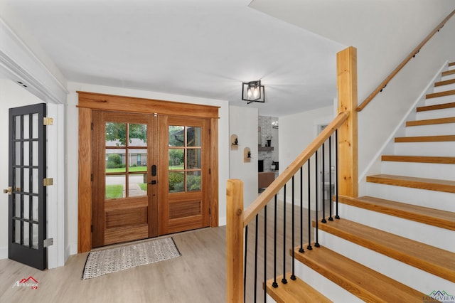 foyer with a fireplace, light hardwood / wood-style flooring, and french doors