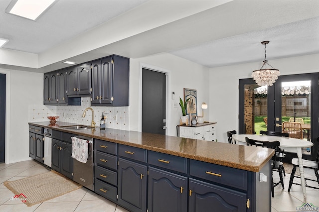 kitchen featuring kitchen peninsula, tasteful backsplash, blue cabinets, sink, and a notable chandelier