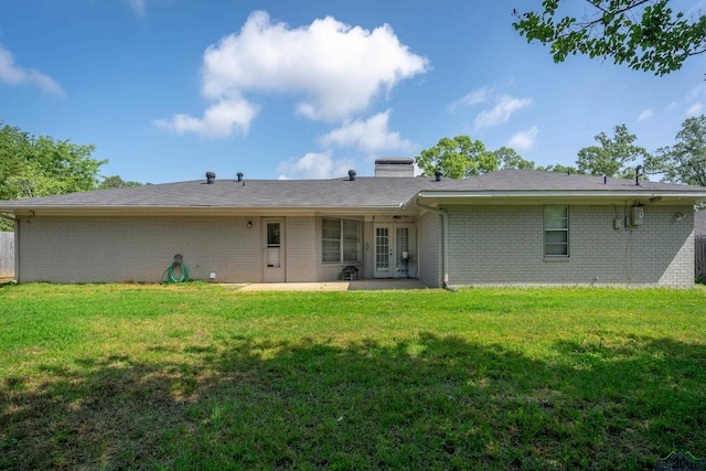 rear view of house featuring a lawn, brick siding, a patio, and french doors